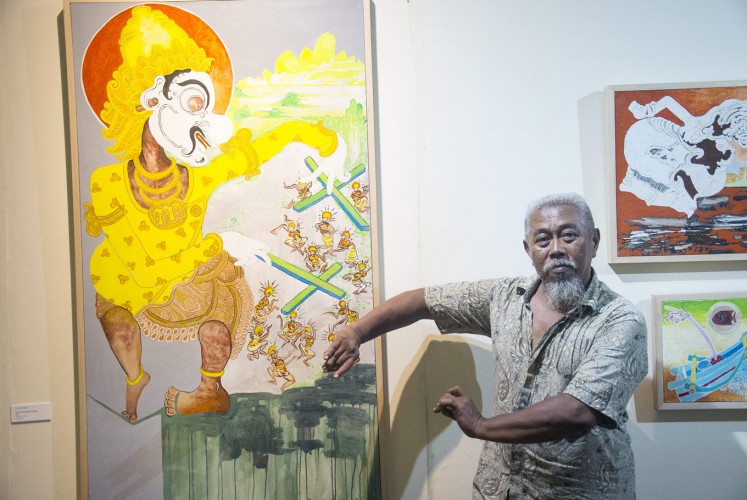 Puppet show: Otok Bima Sidarta poses next to his painting, titled Dibawah Kekuasaan Gareng (Under Gareng’s Rule).