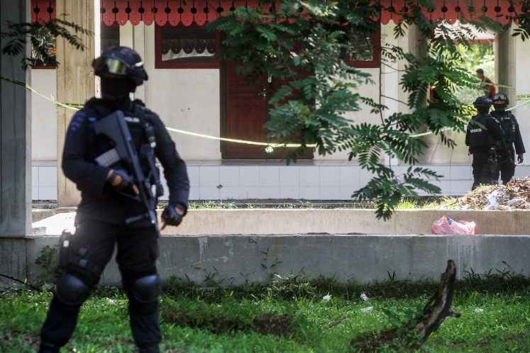 Police officers stand guard in front of a student facility building in Riau University in Pekanbaru, Riau province on June 2. Students and alumni often spend the night in such buildings.