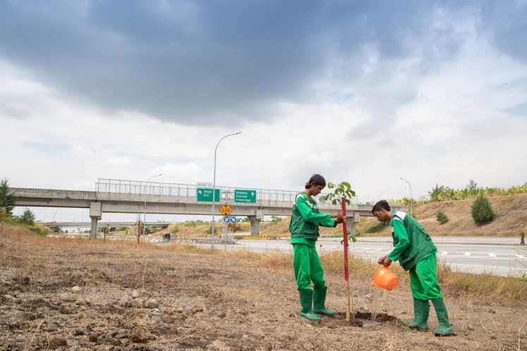 Planting saplings: Workers plant trembesi saplings on the side of a highway connecting Gempol district and Pasuruan regency in East Java.