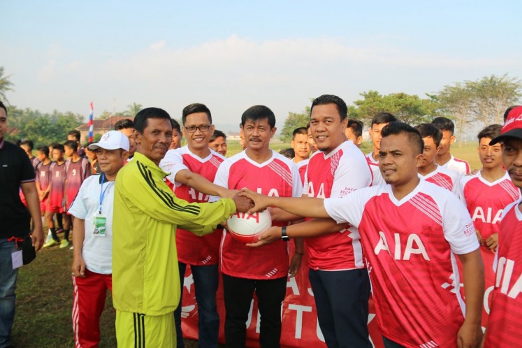 Charity program: PT AIA financial event and sponsorship manager Mohammad Rizki Wardhani (second right) and national soccer coach Indra Sjafri (center) pose for a photograph at a ceremony where AIA’s donated 500 balls to children in Pringsewu regency, Lampung.