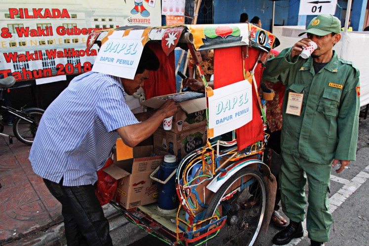 Election officials get some coffee provided by community unit RW 02 in Cibadak subdistrict, Astana Anyar district, Bandung, West Java, during the West Java gubernatorial election on June 27. 