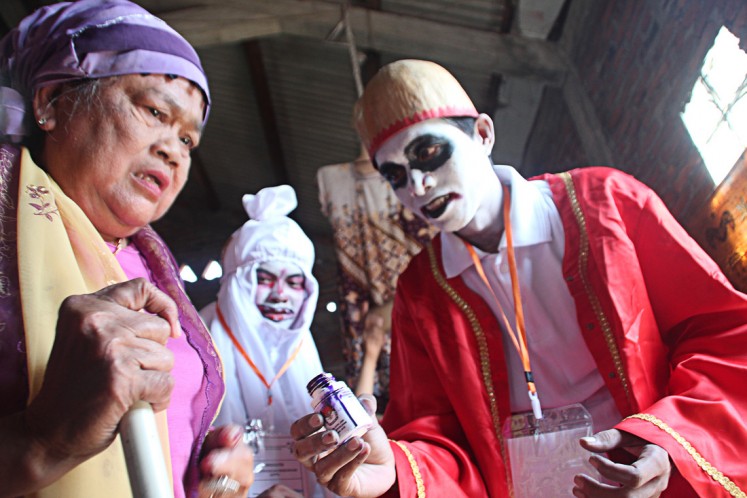 Don't be afraid: A voter looks scared when she has to put her finger in an ink bottle offered by a polling officer wearing a ghost costume after casting her vote on June 27.