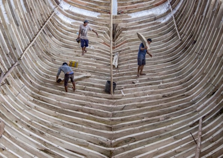 This picture taken on July 7, 2018 shows shipbuilders working on a traditional Pinisi boat in Tana Beru, on South Sulawesi island. 