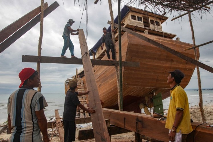 This picture taken on July 7, 2018 shows shipbuilders working on a traditional Pinisi boat in Tana Beru, on South Sulawesi island. 