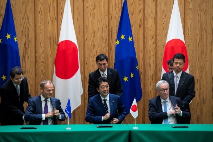 Japanese Prime Minister Shinzo Abe (center) signs an agreement with European Council President Donald Tusk (left) and European Commission President Jean-Claude Juncker (right) at the Prime Minister's Office in Tokyo on July 17, 2018. 