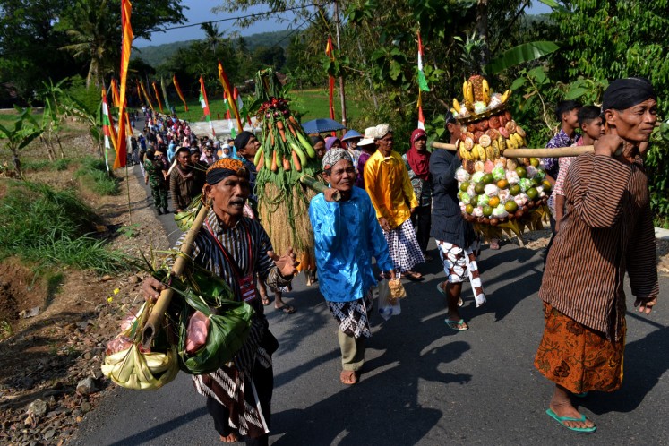 Residents carry offerings as they walk to the forest. 
