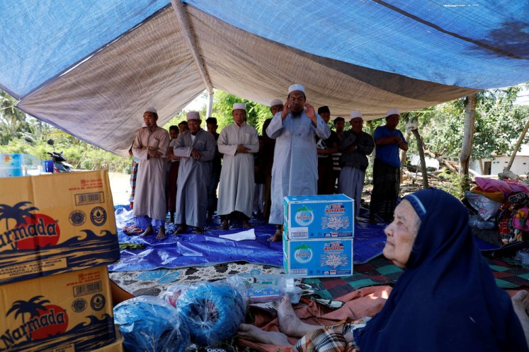 Villagers hold evening prayer inside a temporary shelter after an earthquake hit Lombok island in Pamenang, Indonesia August 6, 2018. 