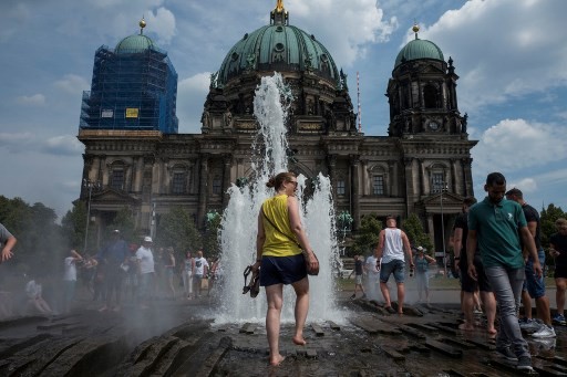 People walk in a fountain in front of the Berlin Cathedral as the heatwave in Europe continues with temperatures reaching 33 degrees Celsius in Berlin on August 4, 2018. 
