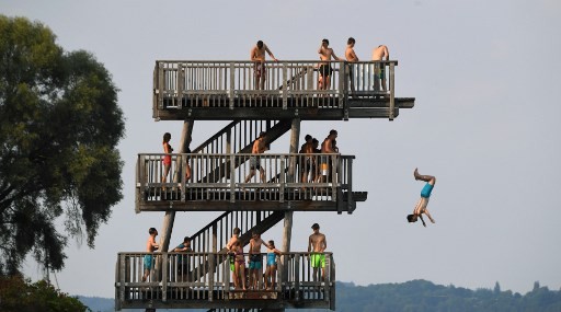 People line up to jump off a diving tower on the shore of the lake Ammersee near the small Bavarian village of Utting, southern Germany, as the heatwave in Europe continues with temperatures reaching over 30 degrees Celcius during the late afternoon on August 4, 2018. 
