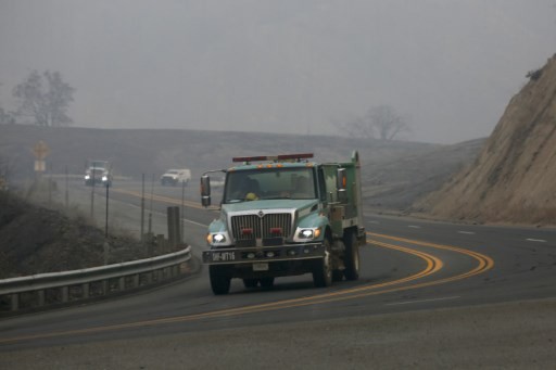 Fire engines drive through smoke from the Carr Fire on July 30, 2018 west of Redding, California. Six people have died in the massive fire, which has burned over 100,000 acres and forced thousands to evacuate since it began on July 23. 