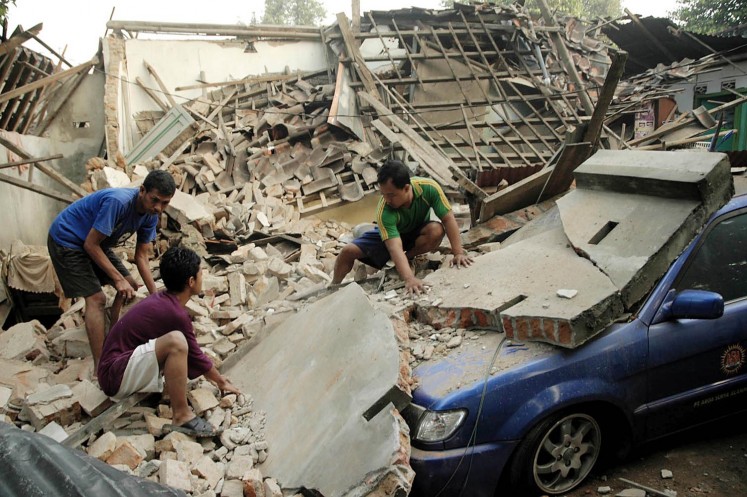 Residents try to remove concrete rubble from on top of their car after a strong earthquake in Yogyakarta on May 27, 2006.  