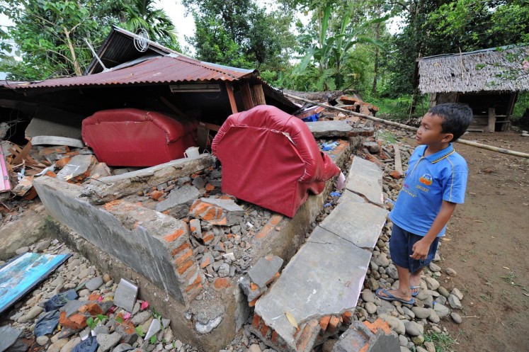 A boy looks at his flattened home after a 7.6-magnitude earthquake hit Padang, Sumatra, in October 2009. 
