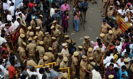 Indian policemen stand guard as supporters of the Dravida Munnetra Kazhagam party gather in front of the hospital where President M. Karunanidhi died, in Chennai on August 7, 2018. Thousands of people desanded into mourning on August 7 in southern India after the death of revered 94-year-old political leader Muthuvel Karunanidhi.
