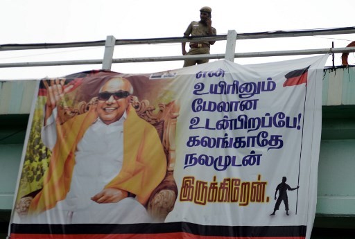 An Indian policeman stands next to a banner with the picture of Dravida Munnetra Kazhagam (DMK) party President M. Karunanidhi at the hospital where he is being treated, in Chennai on August 6, 2018. 
