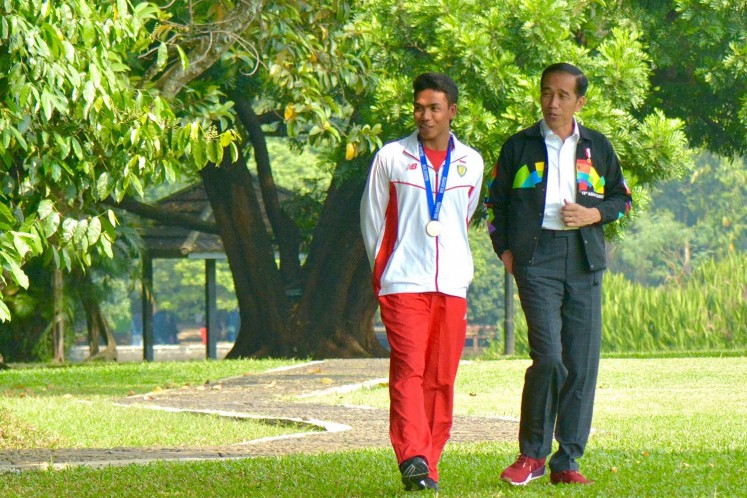 Young sprinter Lalu Muhammad Zohri (left) walks with President Jokowi.