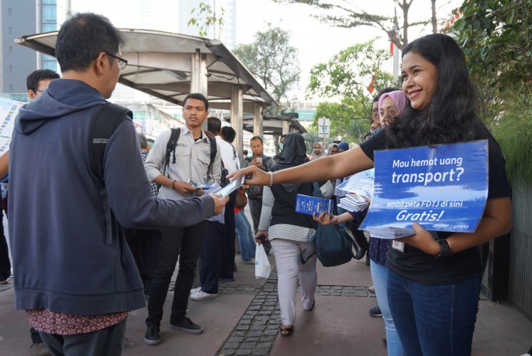 Sharing is caring: A member of the FDTJ hands out the 'Public Transportation Map and Guide' to commuters in Central Jakarta. 