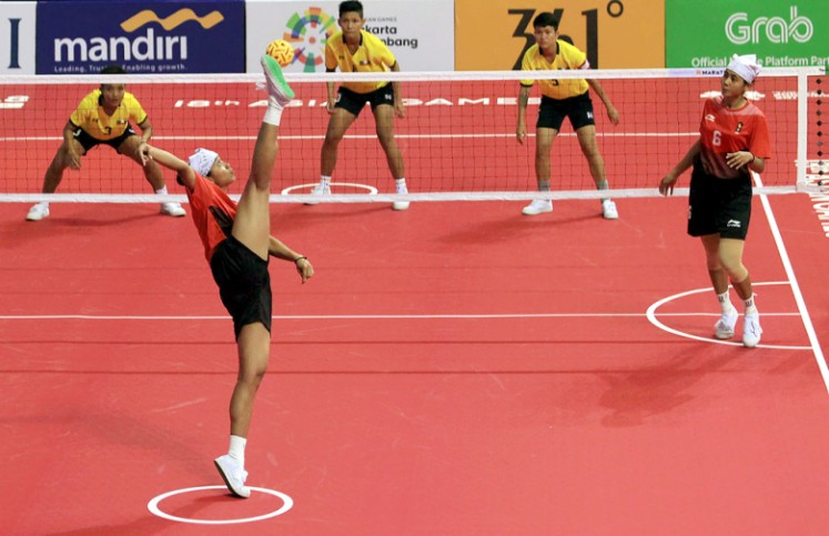 Indonesia’s Leni (left) kicks the ball while her twin sister Lena (right) looks on during their sepak takraw women’s team regu match against Myanmar in the 2018 Asian Games at Ranau Hall in Jakabaring Sports City in Palembang, South Sumatra on Aug. 19.