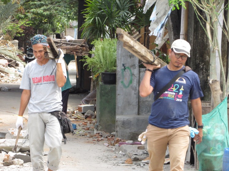 Villagers salvage building materials from their damaged homes to build better temporary housing while the government's post-disaster reconstruction program builds permanent houses for them. 