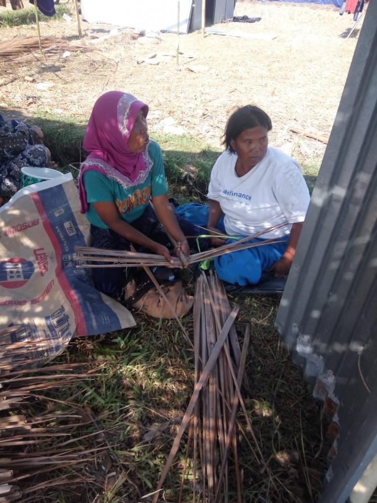 Earthquake survivors weave palm leaves into roof panels for their temporary houses on Lombok Island, West Nusa Tenggara.