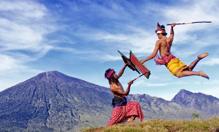 Fighting spirit: Two Lombok men in West Nusa Tenggara engage in the local martial art of peresean, where they fight one another using sticks and protect themselves with rattan armor. 