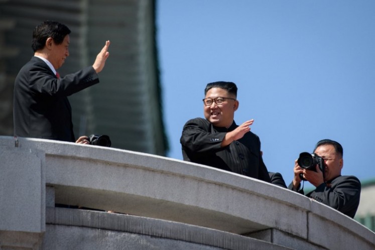 North Korea's leader Kim Jong Un (C) waves with China's Chairman of the Standing Committee of the National People's Congress Li Zhanshu (L) from a balcony of the Grand People's House on Kim Il Sung square following a military parade and mass rally in Pyongyang on September 9, 2018. Thousands of North Korean troops followed by artillery and tanks paraded through Pyongyang on September 9 as the nuclear-armed country celebrated its 70th birthday, but it refrained from displaying the intercontinental ballistic missiles that have seen it hit with sanctions.