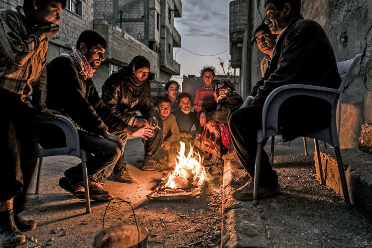 Reality bites: Syrian Kurds gather around a fire in the city of Kobane. After the liberation, most houses were left without electricity or running water and food was also hard to find (March 2015).