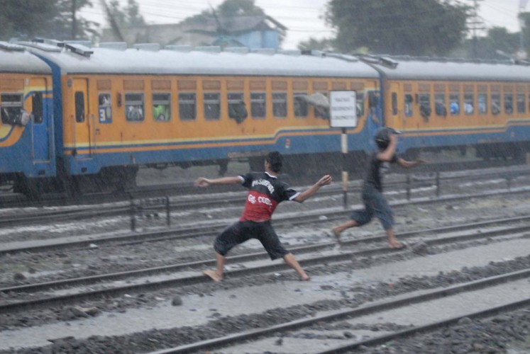 Two teenagers are seen throwing rocks at a Pasundan Train carrying Persebaya supporters at Purwosari Station in Surakarta, Central Java, on Jan. 24.