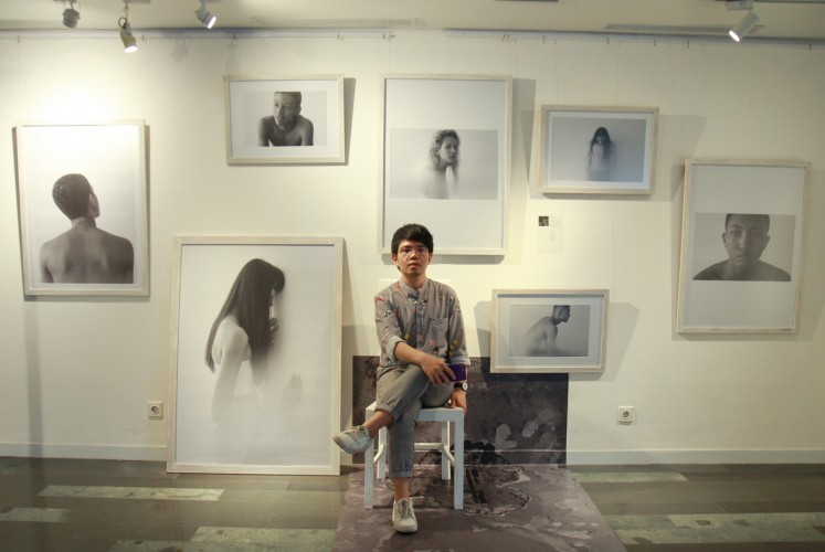 Yon Beni sits in front of his 'Revelare' photos at the 'Chrysalis' fashion photography exhibition on Thursday, Sept. 27 at Artotel Thamrin, Central Jakarta. 