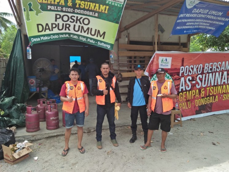 Inmates from Palu detention center in Central Sulawesi gather in front of a public kitchen in Palu, Central Sulawesi, on Oct. 11, while helping survivors.