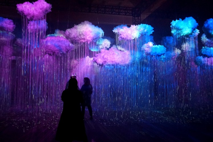 Visitors pose among the artificial clouds and strings at Sembilan Matahari's 'Constellation Neverland'.