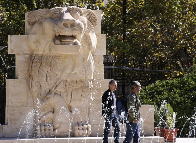 Visitors walk in front of the Lion of al-Lat, an ancient statue from the temple of the same name in Palmyra, during their visit to the national antiquities museum in the Syrian capital Damascus on October 28, 2018. Syria reopened a wing of the capital's famed antiquities museum today after six years of closure to protect its exhibits from the civil war