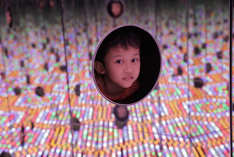 A child visitor peeps through the hole of 'I Want to Love on a Festival Night' (2015), an interactive installation at Yayoi Kusama's exhibition Life is the Heart of a Rainbow, which was held at Museum Macan  from May 12 to Sept. 9.