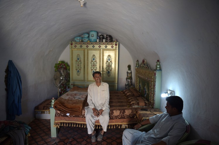 Pakistani villager Ameer Ullah Khan (L) chats with a friend in his cave room in Nikko village, about 60 kilometres from the capital Islamabad, near the highway town Hasan Abdal.