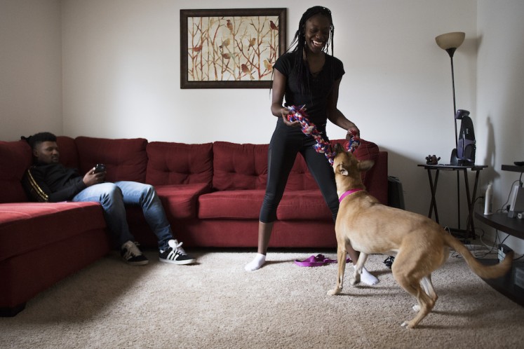Professional wrestler Gia Scott (R) plays with her boyfriend and professional wrestler Deion Epps'(L) dog as he plays on his smartphone at their home in Severn, Maryland, on October 26