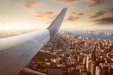 An aircraft flies over New York City, as seen from an overwing perspective. 