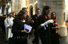 n injured airport worker caries a single candle as she walk in the procession during an ecumenical service for the victims of the Brussels bomb attacks at the Cathedral of St. Michael and St. Gudula in Brussels, Monday, March 28, 2016.  The Belgian Health Minister Minister Maggie De Block says four of those wounded in the suicide bombings last week have died in the hospital, bringing the number of victims of the bombings to 35. 