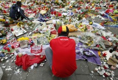 Two men help re-adjust the tributes left for the victims of the recent bomb attacks in Brussels, following heavy rain in the Place de la Bourse in Brussels, Monday, March, 28, 2016. The Belgian health minister says four of those wounded in the suicide bombings last week have died in the hospital.