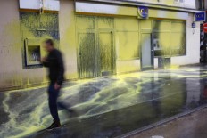 A man walks past a LCL bank covered with yellow paintings by masked demonstrators as youth demonstrate in Paris, Thursday, March 31, 2016. Student organizations and employee unions have joined to call for protests across France to reject the Socialist government's bill, which they consider as badly damaging hard-fought worker protections. AP/Francois Mori