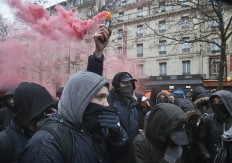 A masked student holds a flare during a rally to protest the new labor law in Paris, Thursday, March 31, 2016. Students and workers hold street protests across France while train drivers, teachers and others are on strike to reject a government reform relaxing the 35-hour workweek and other labor rules. AP/Michel Euler