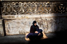 In this Tuesday, March 15, 2016 photo, a Syrian refugee woman holds her child as she begs for money on a sidewalk, in Beirut, Lebanon. It is one of the most visible signs of the refugee crisis that has put an immense strain on neighboring countries and destabilized Europe. On Lebanon shopping streets, roundabouts and traffic lights, child beggars are seen pressing their small faces against windows of cars, stretching their hands for money or selling chewing gum or flowers. 