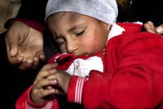 In this Friday, March 25, 2016 photo, a Syrian refugee woman holds her child as she begs for money on a sidewalk, in Beirut. Lebanon is home to more than 1 million registered Syrian refugees, or nearly a quarter of the country's 4.5 million people, the highest refugee population in the world per capita. 