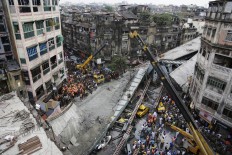 Excavator machines remove debris of a partially collapsed overpass in Kolkata, India, Friday, April 1, 2016. The overpass spanned nearly the width of the street and was designed to ease traffic through the densely crowded Bara Bazaar neighborhood in the capital of the east Indian state of West Bengal. About 100 meters (300 feet) of the overpass fell, while other sections remained standing. 