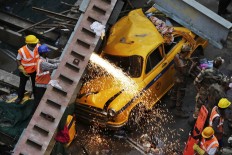 A damaged three-wheeled vehicle is taken out from the rubble of a collapsed overpass in Kolkata, India, Friday, April 1, 2016. The overpass spanned nearly the width of the street and was designed to ease traffic through the densely crowded Bara Bazaar neighborhood in the capital of the east Indian state of West Bengal. About 100 meters (300 feet) of the overpass fell, while other sections remained standing. 