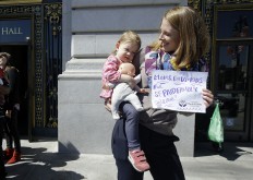 Kim Turner holds her daughter Adelaide Turner Winn before a rally supporting paid family leave at City Hall in San Francisco, Tuesday, April 5, 2016. The San Francisco Board of Supervisors is voting on whether to require six weeks of fully paid leave for new parents - a move that would be a first for any jurisdiction.
