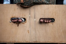 The feet of one of the female farmers are seen cemented into a wooden crate. The Jakarta Post/Seto Wardhana