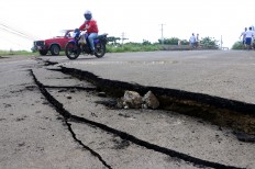 Vehicles drive by a fracture on a road caused by a 7.8 earthquake in Manta, Ecuador, Sunday, April, 17, 2016. A powerful, 7.8-magnitude earthquake shook Ecuador's central coast on Saturday, killing hundreds and spreading panic as it collapsed homes. AP Photo/Patricio Ramos