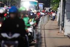 Alfini walks on the sidewalk at Jalan Sudirman Jakarta while a group of motorcycles attempting to avoid traffic by trespassing on a sidewalk on Monday. She took action to protest unruly bikers. The Jakarta Post/ Dhoni Setiawan