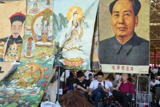 Vendors wait for customers at a curio market near a display of former Chinese leader Mao Zedong alongside images of emperors and deities in Beijing, China, Monday, May 16, 2016.  AP Photo/Ng Han Guan
