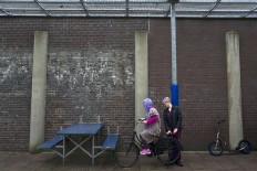 In this Monday, May 2, 2016 photo, a Dutch volunteer teaches an Afghan refugee woman how to ride a bicycle at a yard in the former prison of De Koepel in Haarlem, Netherlands. With crime declining in the Netherlands, the country is looking at new ways to fill its prisons. AP Photo/Muhammed Muheisen