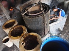 A worker stokes a fire to distill the fermented sugarcane juice. JP/ Ganug Nugroho Adi